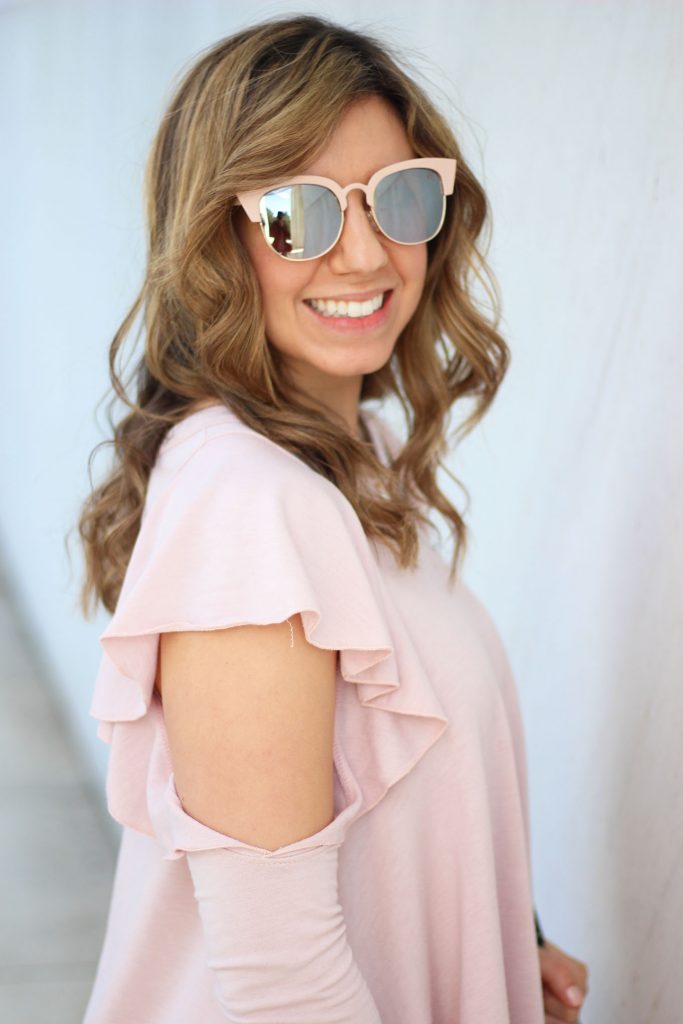 Lifestyle blogger Roxanne Birnbaum of Glass of Glam wearing a Red Dress Boutique pink ruffle top, Old Naby distressed denim, and a JustFab rose gold bag