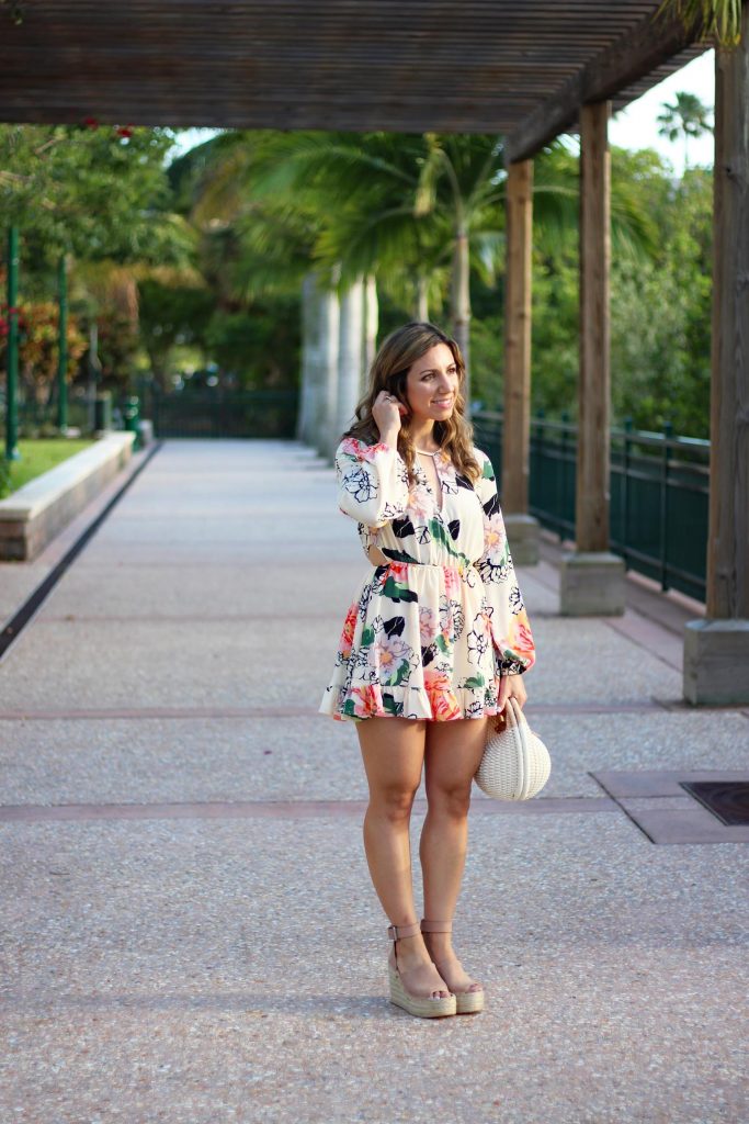 Lifestyle Blogger Roxanne Birnbaum of Glass of Glam in a Floral Ruffle Zaful romper, Marc Fisher Wedge Espadrilles, and a Zaful Basket Bag