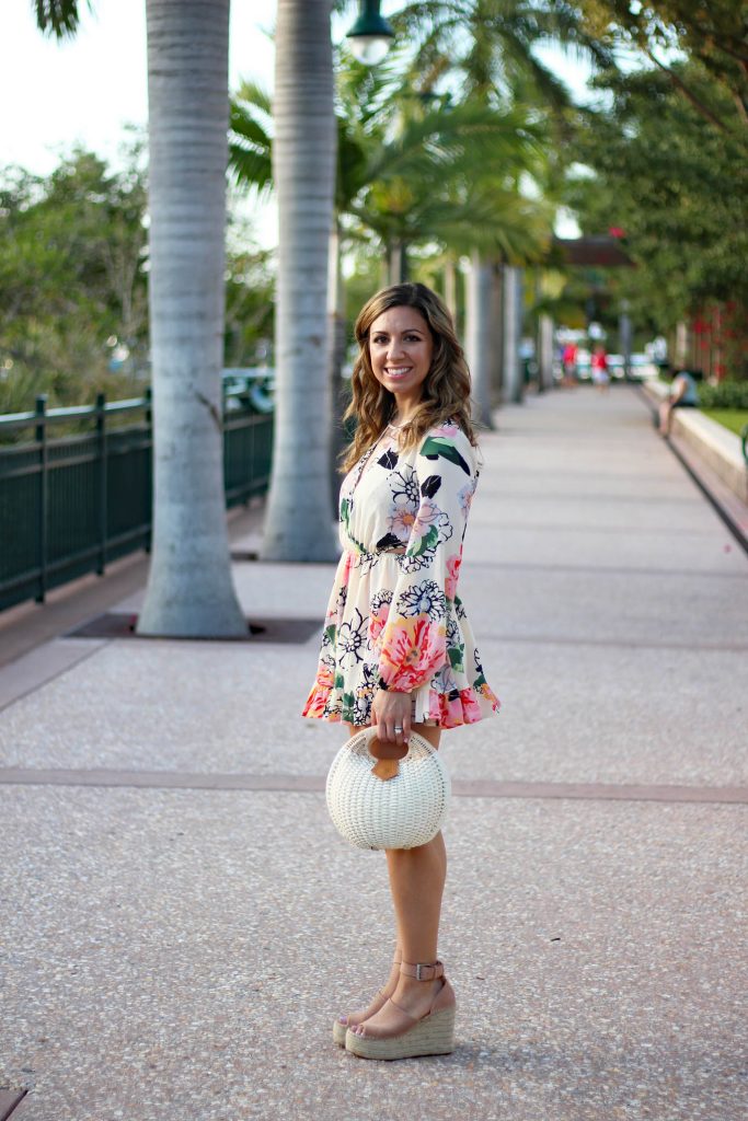 Lifestyle Blogger Roxanne Birnbaum of Glass of Glam in a Floral Ruffle Zaful romper, Marc Fisher Wedge Espadrilles, and a Zaful Basket Bag