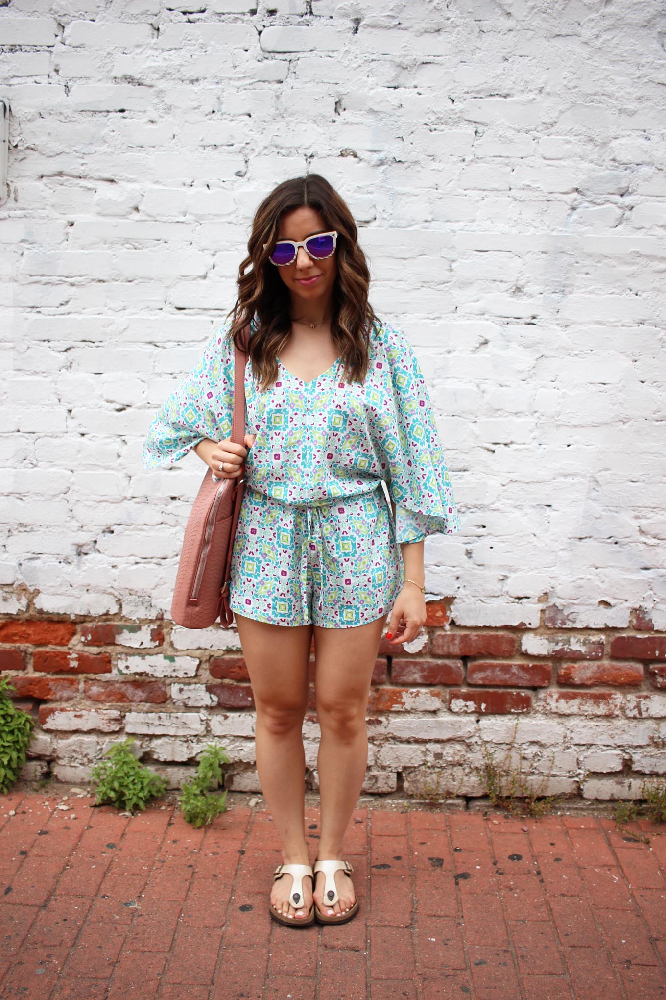Lifestyle blogger Roxanne of Glass of Glam wearing a Cuddy Studios Romper, Winkwood Sunglasses, and a Mel Boteri bag
