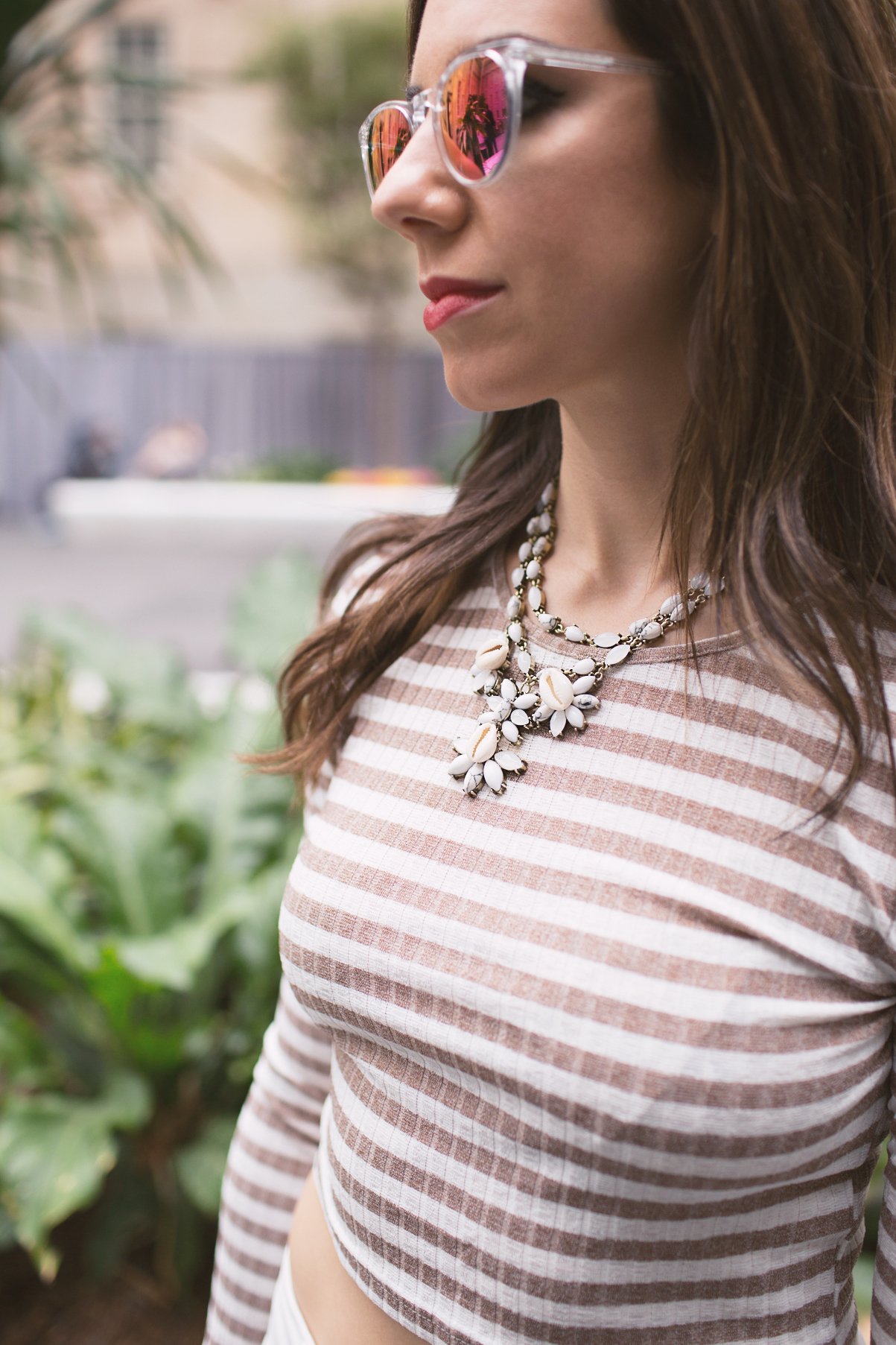 Lifestyle blogger Roxanne of Glass of Glam wearing a striped crop top, Old Navy denim, a baublebar necklace, and warby parker sunglasses
