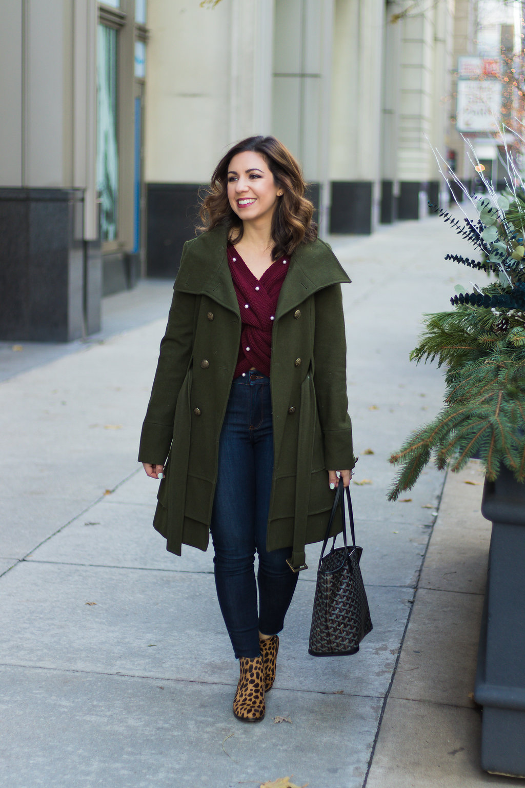 Lifestyle blogger Roxanne of Glass of Glam wearing a pearl burgundy sweater, green military jacket, Mott + Bow denim, and leopard booties