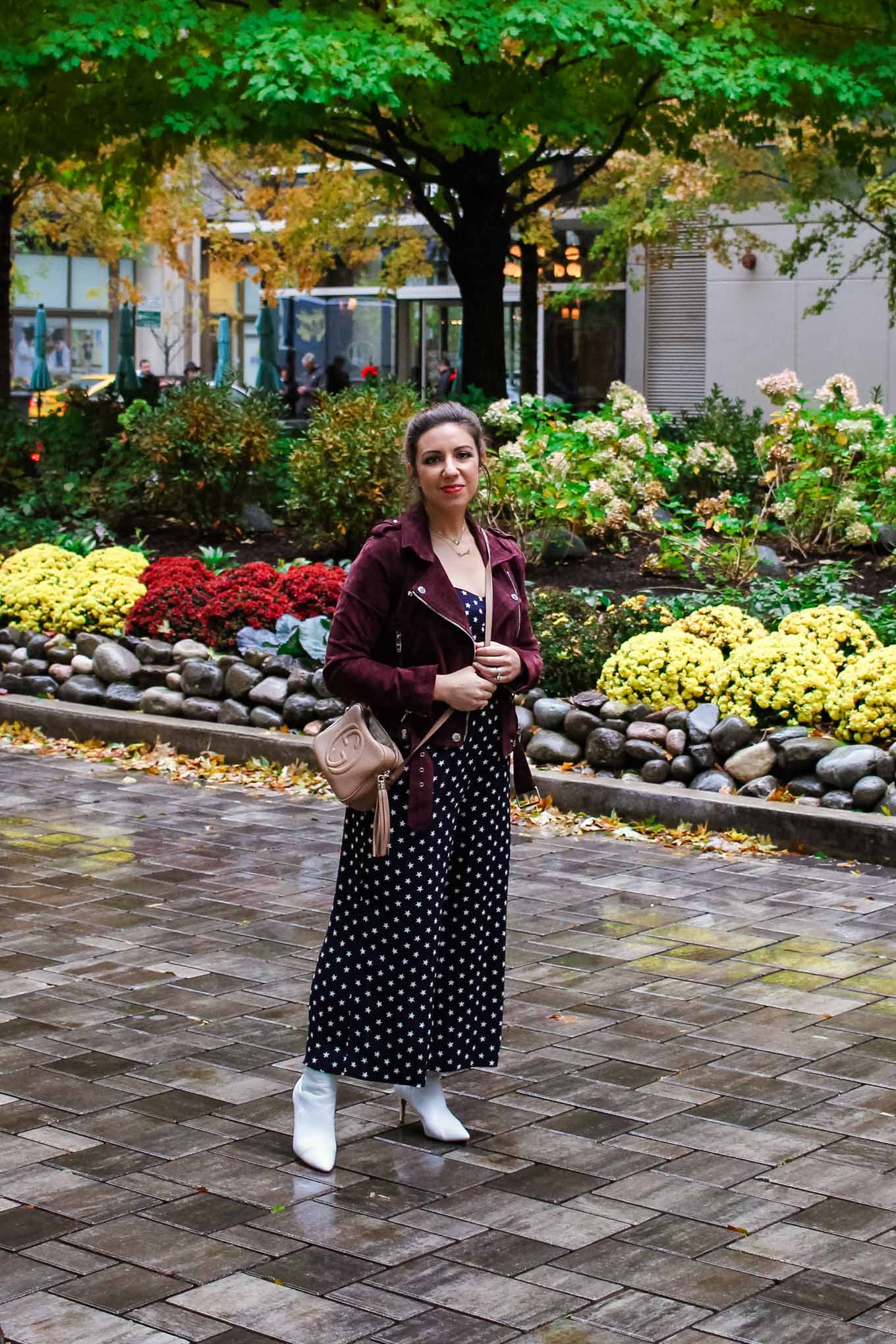 Lifestyle blogger Roxanne of Glass of Glam wearing a J.Crew star print jumpsuit, BlankNYC jacket, Halogen white booties, and a Gucci soho disco bag
