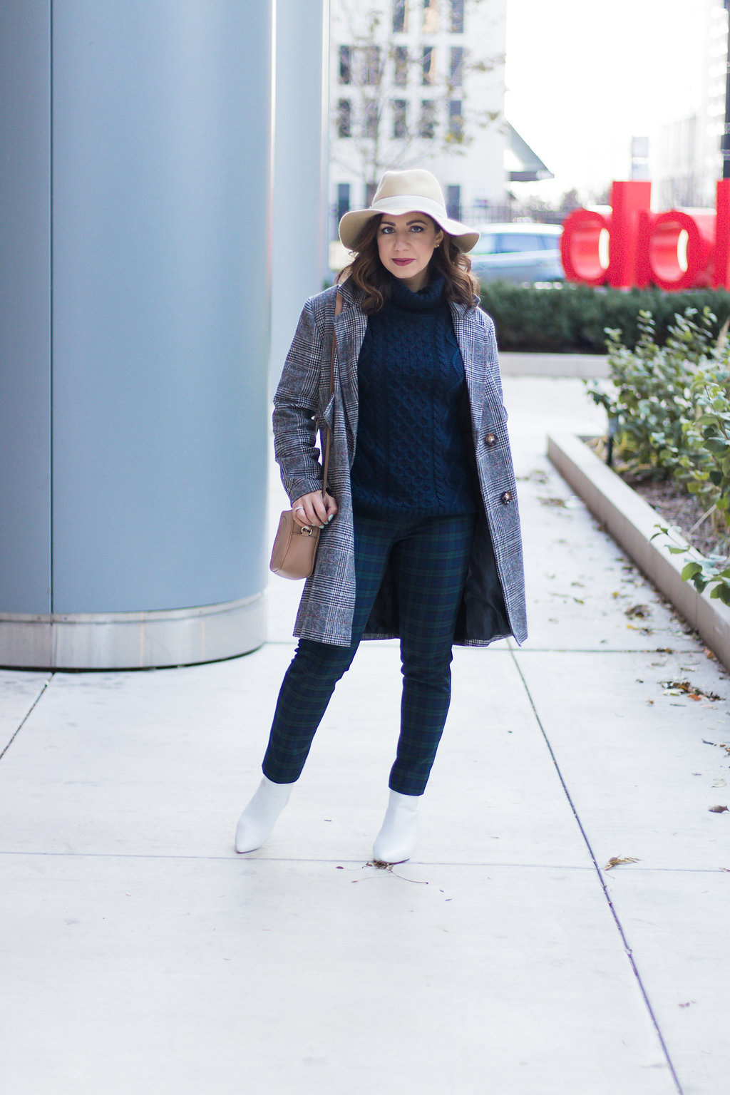 Lifestyle blogger Roxanne of Glass of Glam wearing plaid pants, a plaid coat, felt fedora, and a cable knit sweater