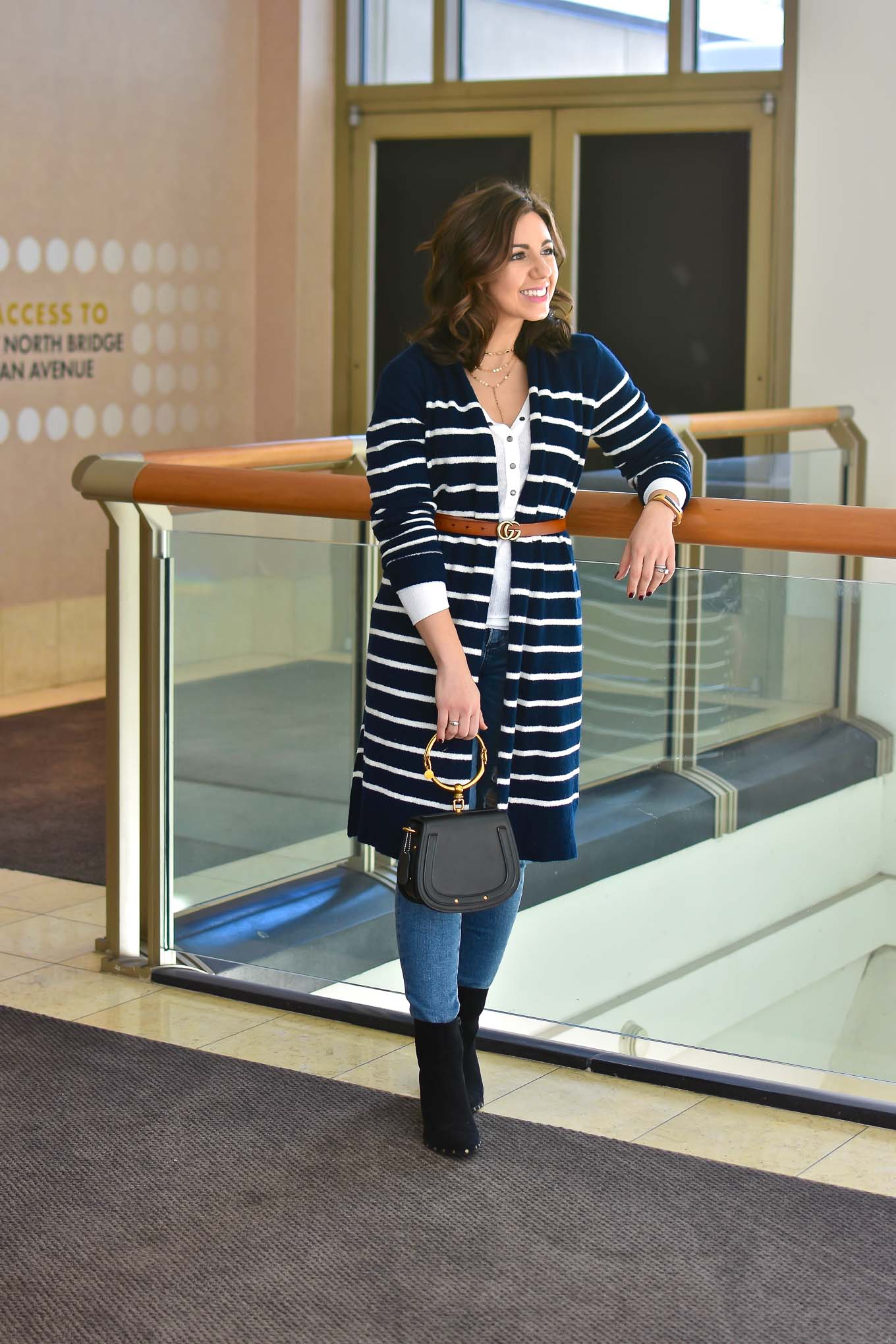 Lifestyle blogger Roxanne of Glass of Glam wearing an Old Navy cardigan, Urban Outfitters Henley, Agolde denim, Justfab booties, a Gucci belt replica (Gucci Dupe), and a Chloe Nile Dupe - Designer Dupes, White & Blue by popular DC fashion blogger Glass of Glam