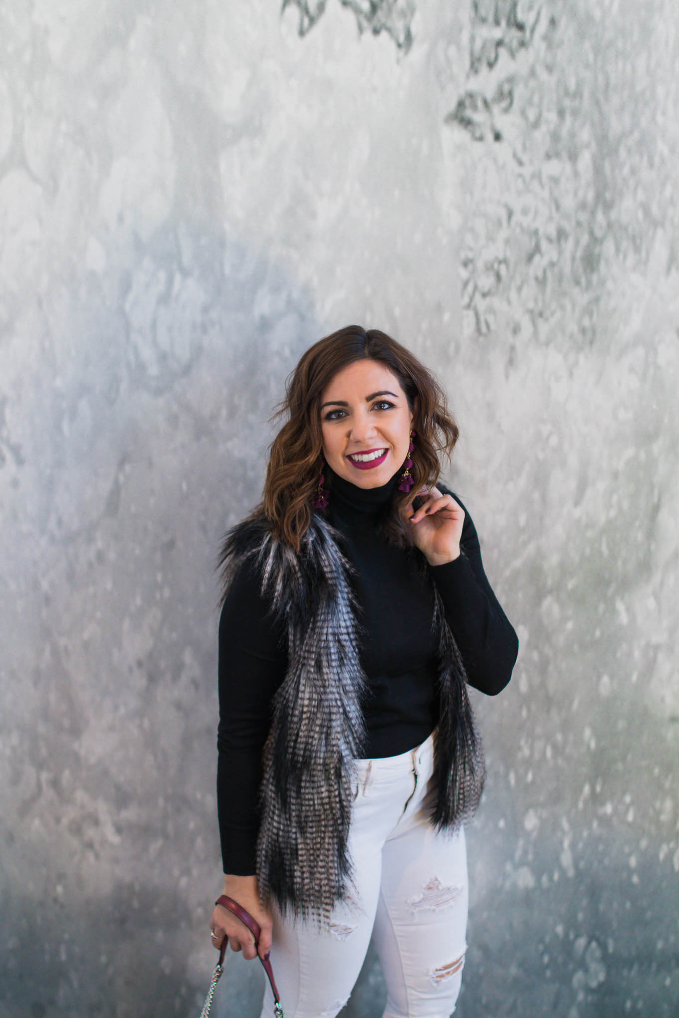 Lifestyle blogger Roxanne of Glass of Glam wearing a faux fur vest, J.Crew turtleneck, Old Navy white denim, and Baublebar earrings