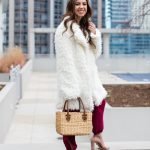 Lifestyle blogger Roxanne of Glass of Glam wearing a shaggy coat, burgundy pants, Sea and Grass straw tote, and a le tote necklace - How I Shoot Blog Photos by popular Chicago style blogger Glass of Glam