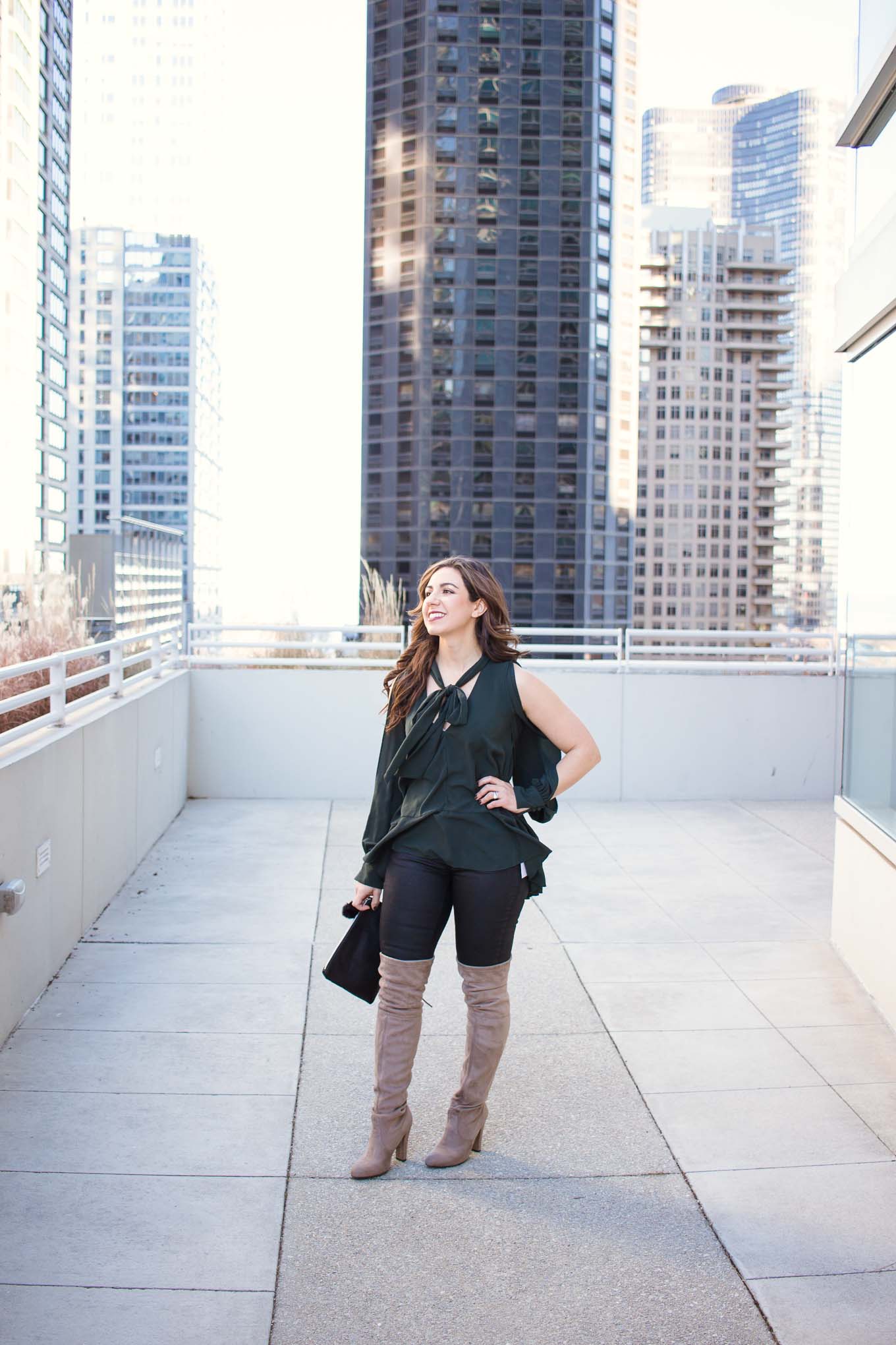Lifestyle blogger Roxanne of Glass of Glam wearing a Le Tote green top, coated denim, cat clutch, and steve madden boots