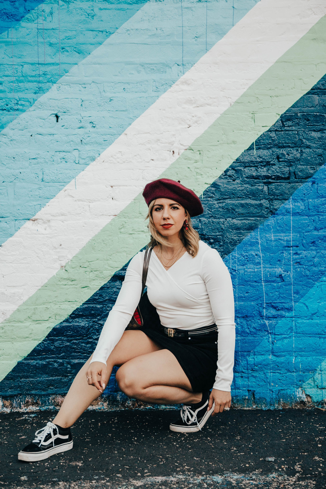 Stay truly informed featured by top US lifestyle blog, Glass of Glam: image of a woman standing in front of a rainbow wall wearing an H&M corduroy skirt, a SheIn bodysuit, Vans Old Skool and a red beret