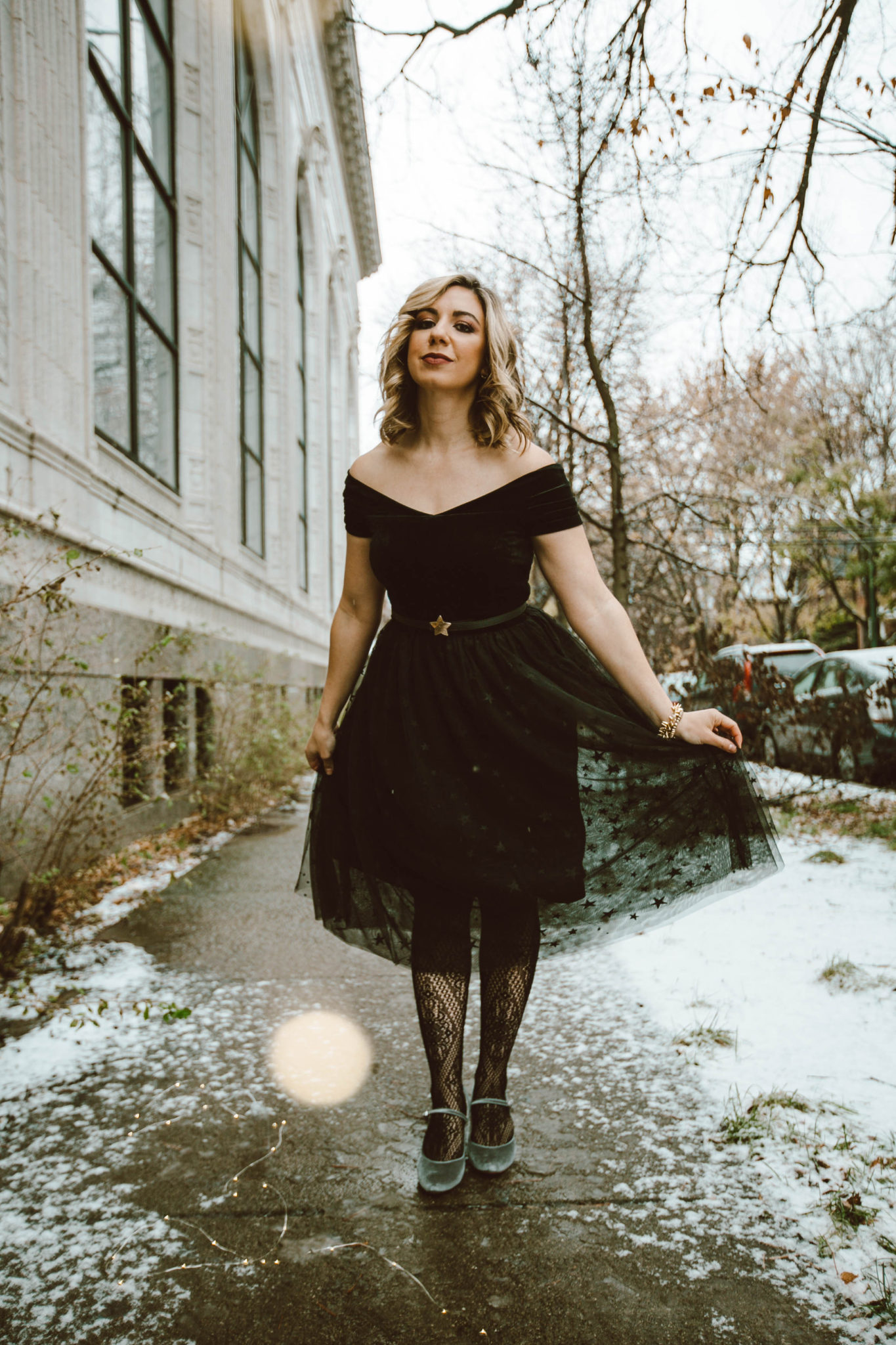 Holiday Cocktail dresses featured by top Chicago fashion blog, Glass of Glam: picture of a blonde woman wearing a modcloth black dress, Modcloth diamond tights, Modcloth velvet heels, Modcloth star belt