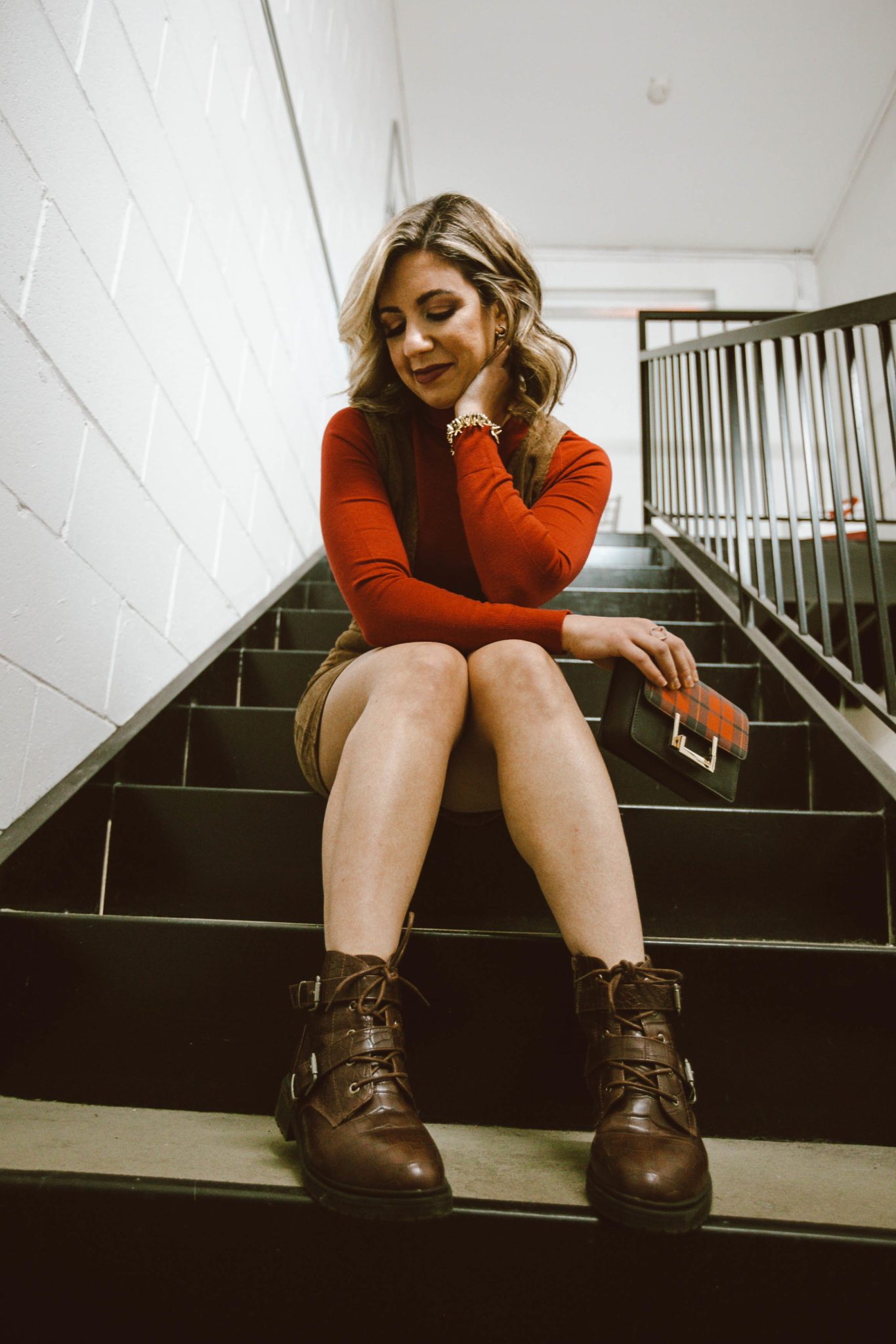 Five Fall Boot Trends by popular Chicago fashion blog, Glass of Glam: image of a woman sitting on some stairs and wearing some brown combat boots.