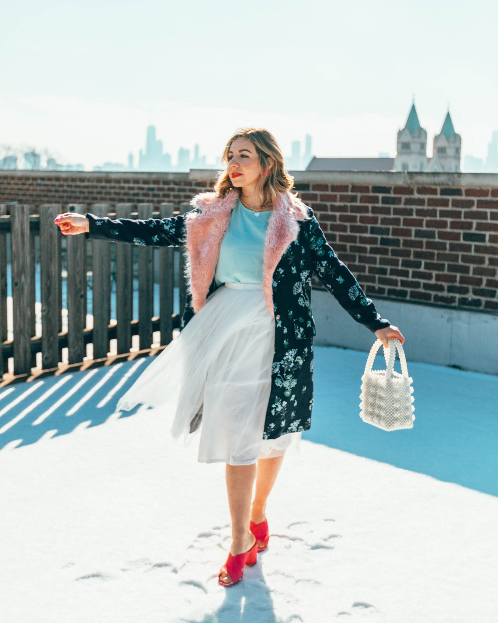 White tulle skirt styled by top US fashion blog, Glass of Glam: image of a woman wearing an ASOS white tulle skirt, SheIn Aqua top, Amazon pink sandals, Rent the Runway floral coat, BaubleBar heart pendant necklace, Baublebar heat earrings and an Amazon beaded handbag
