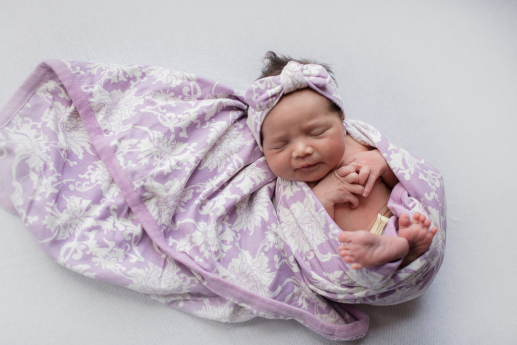 Baby Girl Birth Story: Welcome Sidney Eileen! by popular life and style blog, Glass of Glam: image of a newborn baby wrapped in a purple and white floral print blanket.