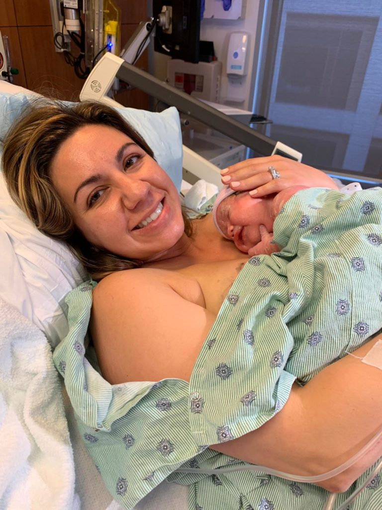 Baby Girl Birth Story: Welcome Sidney Eileen! by popular life and style blog, Glass of Glam: image of a woman wearing a hospital gown, laying down in a bed, and doing skin-to-skin contact with a newborn baby girl in a labor and delivery room at the hospital.