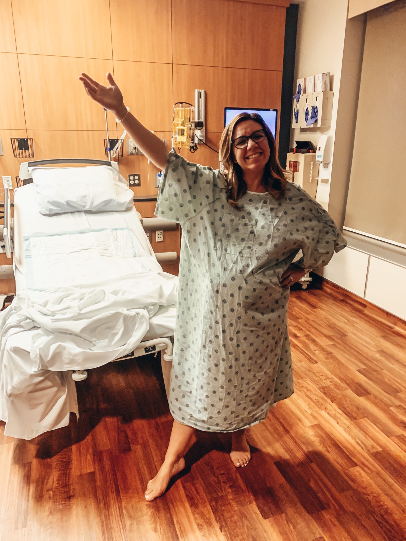 Baby Girl Birth Story: Welcome Sidney Eileen! by popular life and style blog, Glass of Glam: image of a woman wearing a hospital gown and standing in a labor and delivery room at the hospital.
