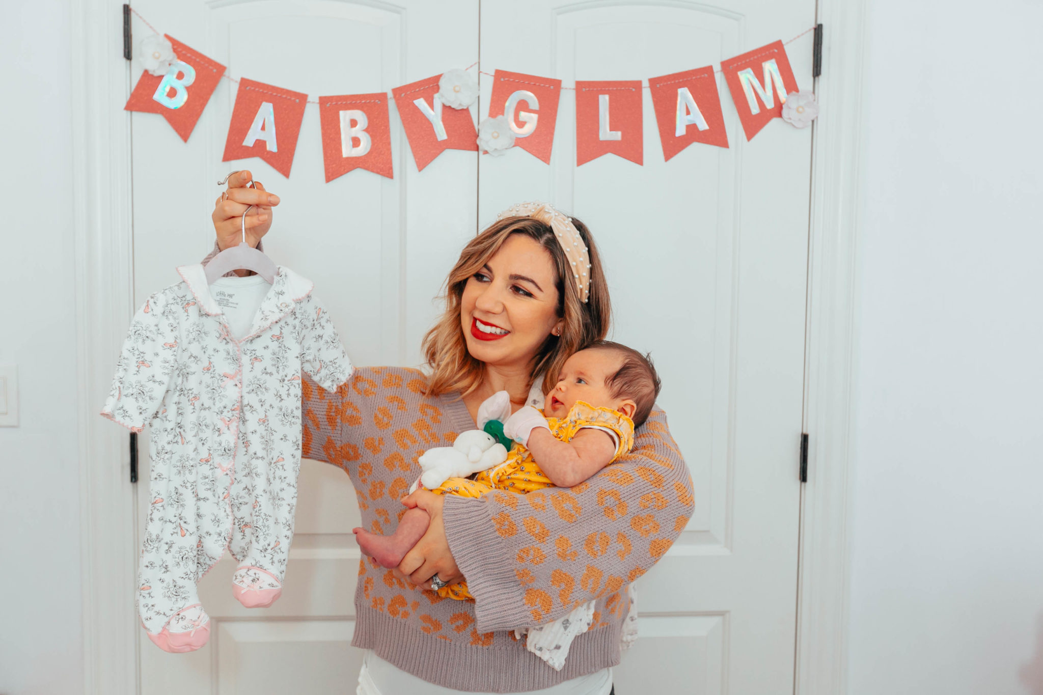 My Favorite Newborn Essentials by popular life and style blog, Glass of Glam: image of a woman holding her newborn baby and a white and pink floral onesie.