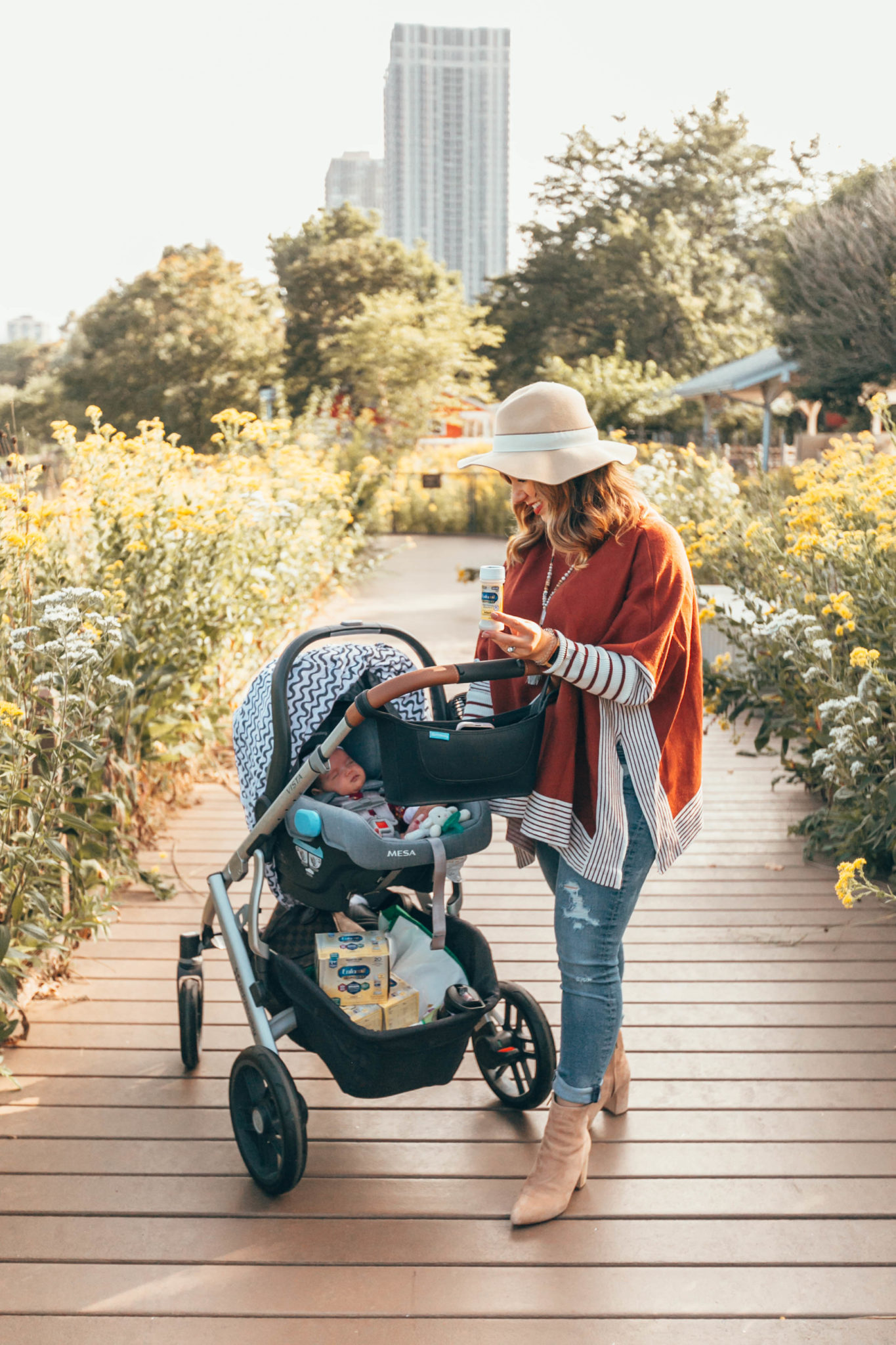 Enfamil NeuroPro Infant Formula Is My Baby Formula Choice by popular Chicago mom blog, Glass of Glam: image of a mom pushing her baby in a stroller outside and holding a bottle of Enfamil NeuroPro Infant Formula. 