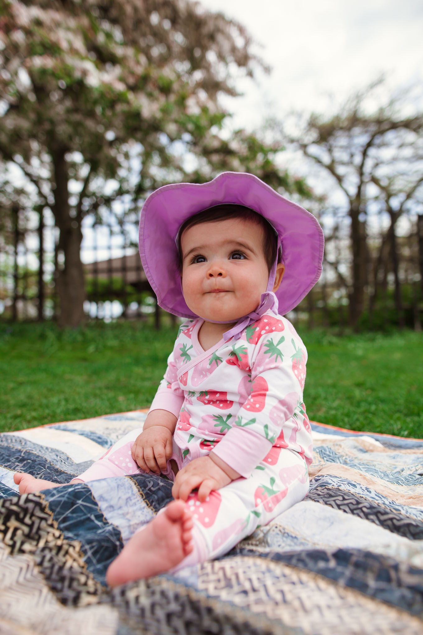 Picnic in the Park by popular Chicago lifestyle blog, Glass of Glam: image of a baby girl wearing a Monica + Andy Kimono Tie One-Piece and green sprouts i play.® by green sprouts® Brim Sun Hat while sitting on a blanket at the park.