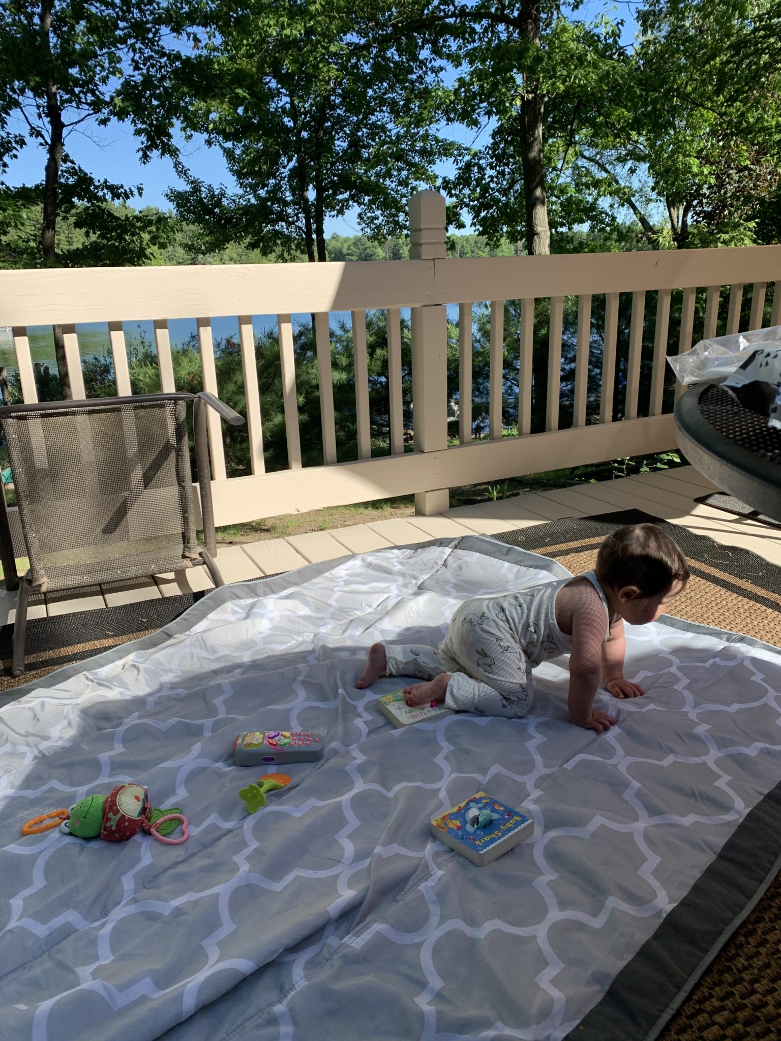 Traverse City by popular Chicago travel blog, Glass of Glam: image of a baby playing on a play mat outside on a back deck.
