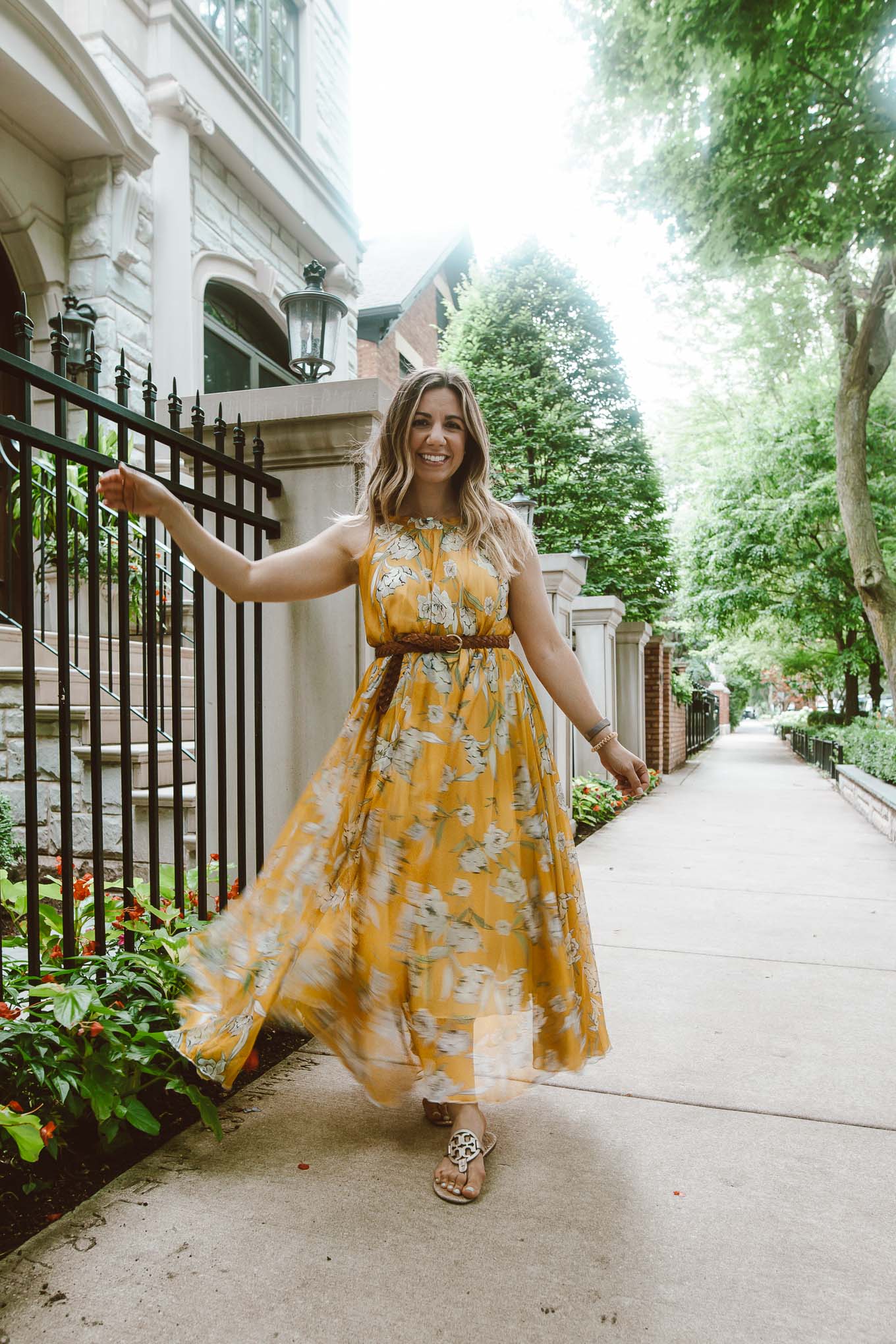 Yellow Dresses by popular Chicago fashion blog, Glass of Glam: image of a woman standing outside and wearing a Chicwish yellow floral maxi dress, thrifted braided belt, and Nordstrom Miller Flip Flop TORY BURCH.