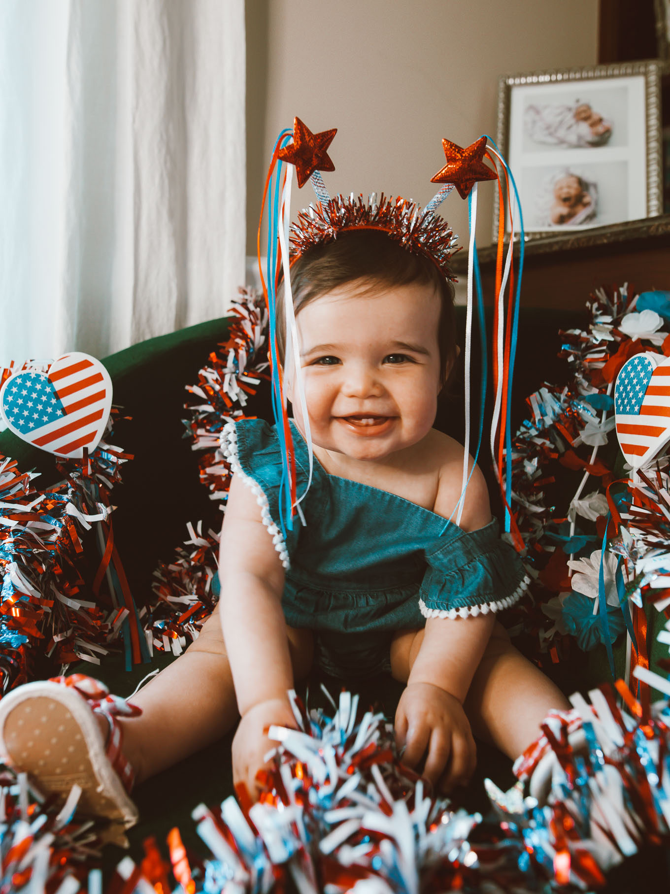 First Birthday by popular Chicago motherhood blog, Glass of Glam: image of a 11 month old baby girl wearing a star head band and sitting in some red, white, and blue garland.