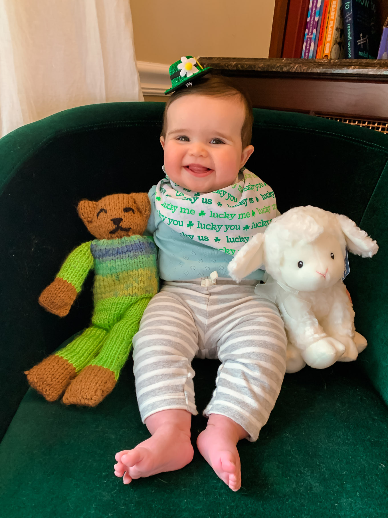 First Birthday by popular Chicago motherhood blog, Glass of Glam: image of a 7 month old baby girl wearing a miniature green leprechaun hat and sitting with a stuffed lamb.