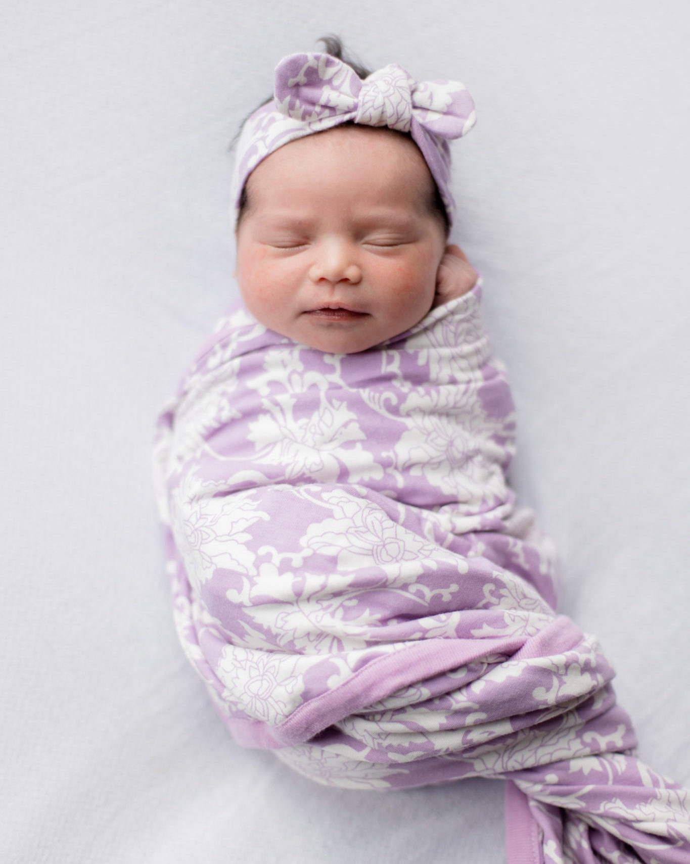 First Birthday by popular Chicago motherhood blog, Glass of Glam: image of a newborn baby wrapped in a purple and white blanket.