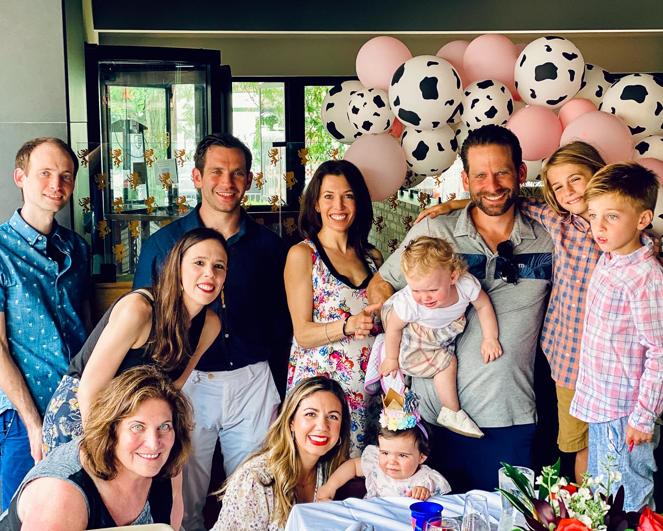 1st Birthday by popular Chicago lifestyle blog, Glass of Glam: image of a family standing next to a Amazon QIYNAO White and Blacke Dairy Cow Happy Birthday Banner, Amazon Cow Print Beverage Napkins, Amazon Finypa Funny Cow Party Decorations Balloon 85pcs Arch Garland.