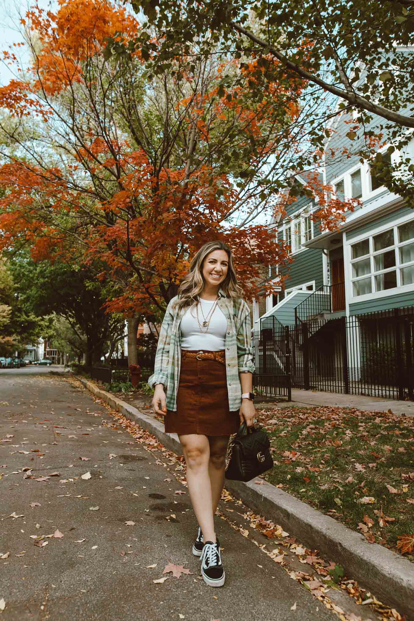 90's Fashion by popular Chicago fashion blog, Glass of Glam: image of a woman walking outside and wearing a corduroy skirt, Vans sneakers, flannel shirt, Target white tank top, Kendra Scott Davis Multistrand Necklace, and holding a Gucci bag. 