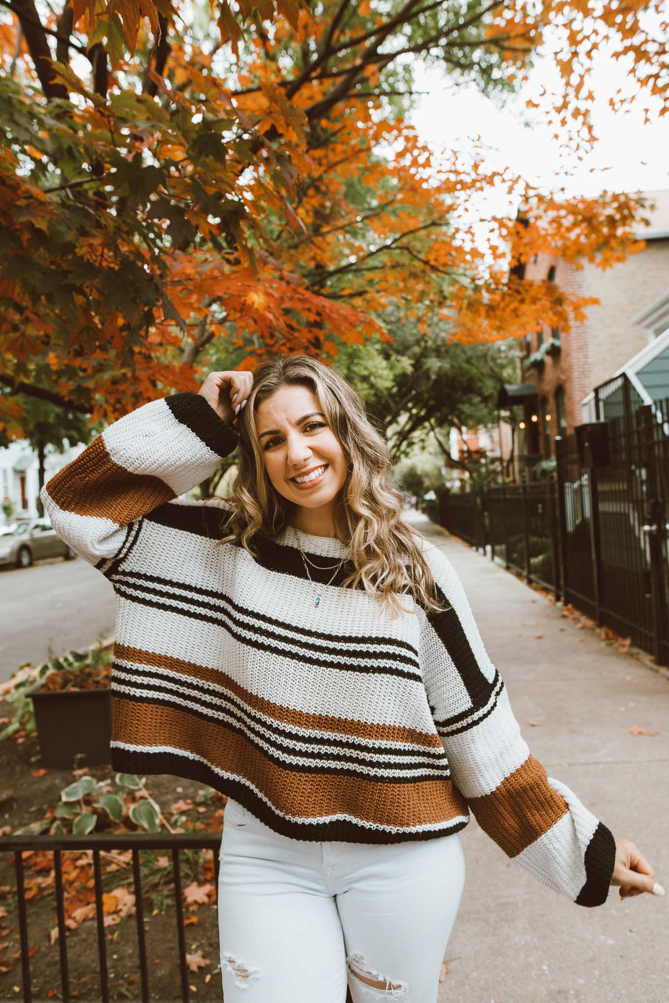 Fall Sweaters by popular Chicago fashion blog, Glass of Glam: image of a woman standing under a tree with orange leaves and wearing a Amazon ZESICA Women's Long Sleeve Crew Neck Striped Color Block Casual Loose Knitted Pullover Sweater, Old Navy Mid-Rise Distressed Rockstar Super Skinny White Ankle Jeans for Women, Gucci Gucci Jordaan GG canvas loafer, and Kendra Scott Elisa Gold Triple Strand Necklace In Abalone Shell.
