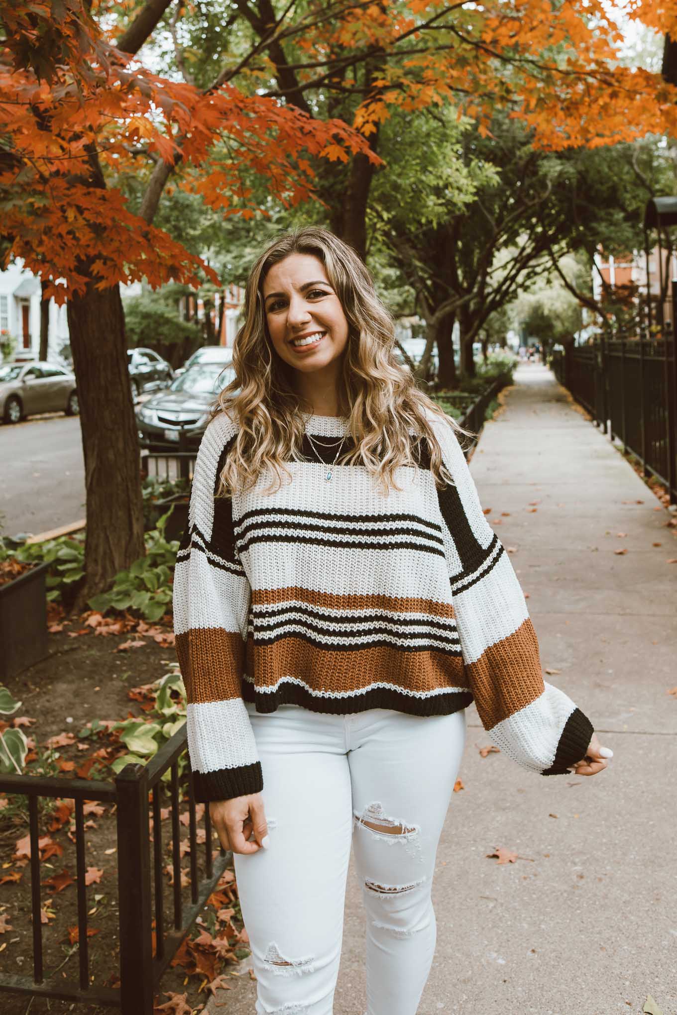 Fall Sweaters by popular Chicago fashion blog, Glass of Glam: image of a woman standing under a tree with orange leaves and wearing a Amazon ZESICA Women's Long Sleeve Crew Neck Striped Color Block Casual Loose Knitted Pullover Sweater, Old Navy Mid-Rise Distressed Rockstar Super Skinny White Ankle Jeans for Women, Gucci Gucci Jordaan GG canvas loafer, and Kendra Scott Elisa Gold Triple Strand Necklace In Abalone Shell.