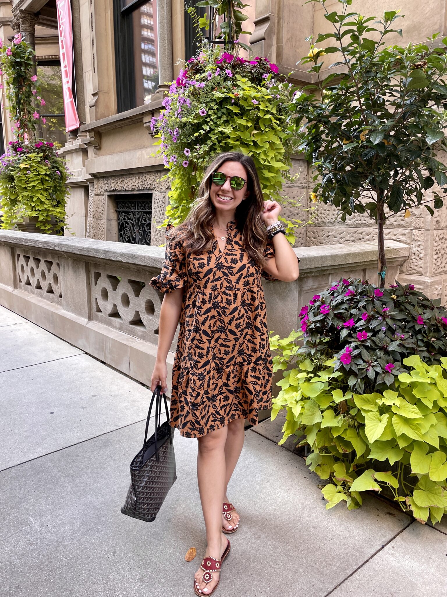 Amazon Dresses by popular Chicago fashion blog, Glass of Glam: image of a woman walking outside and a wearing a brown and black floral print midi dress, Jack Rogers sandals and foster grant sunnies. 